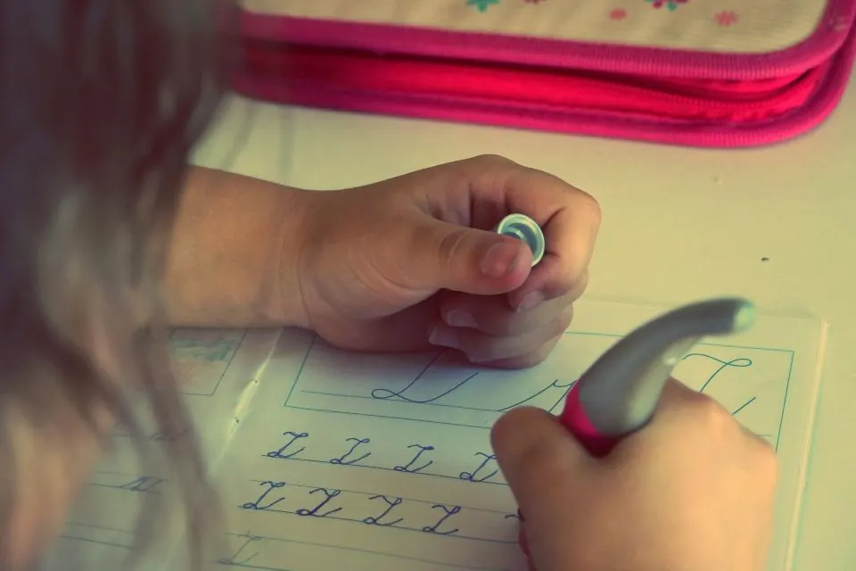 ノートに文字を書く練習をする子どもの手元