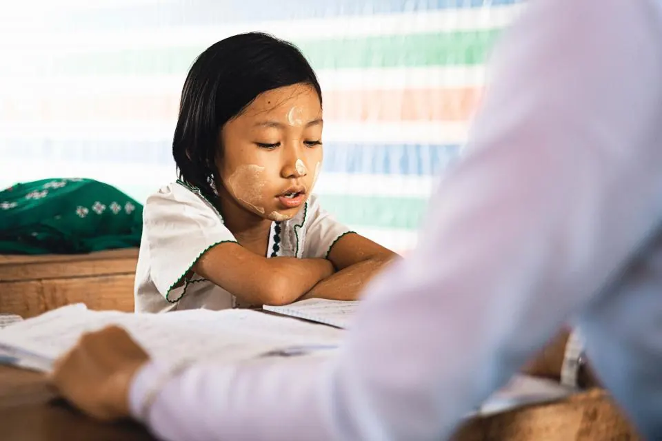 子どもの隣で大人が一対一で勉強を教えている様子